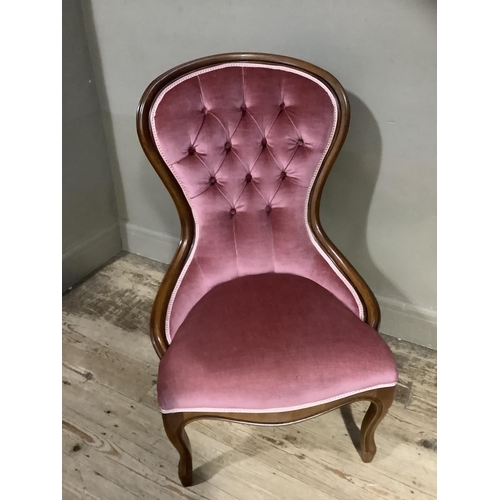 364 - A reproduction Victorian mahogany nursing chair having encircling frame, pink buttoned upholstery an... 