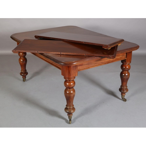 393 - A Victorian mahogany extending dining table, with two leaves, on baluster turned legs with brass cap... 