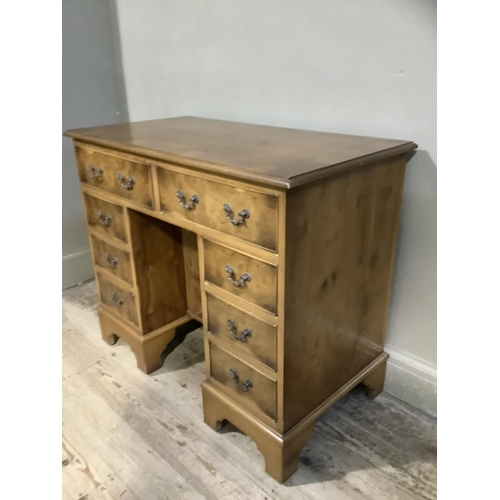 396 - A reproduction yew wood desk, cross banded having two drawers across above a central cupboard to the... 