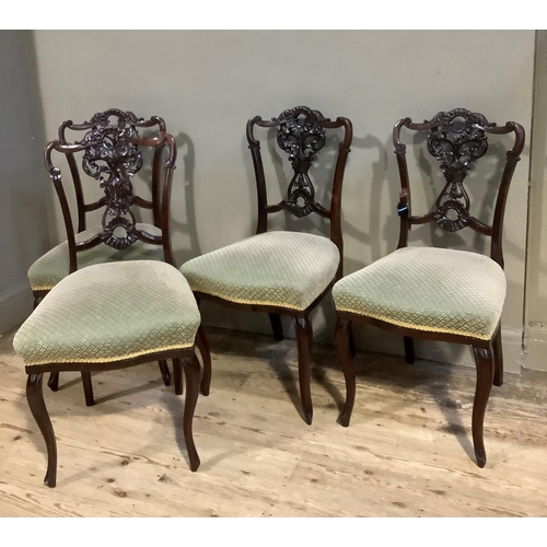 394 - A set of four late Victorian mahogany salon chairs with foliate pierced splats, upholstered seats an... 