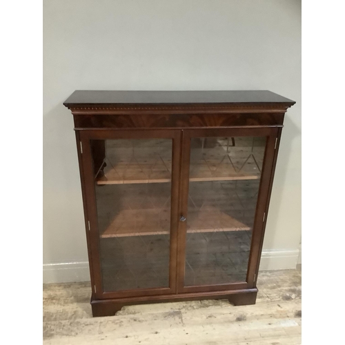 99 - A reproduction mahogany finish two door glazed bookcase on bracket feet