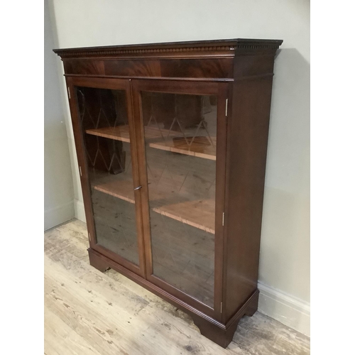 99 - A reproduction mahogany finish two door glazed bookcase on bracket feet