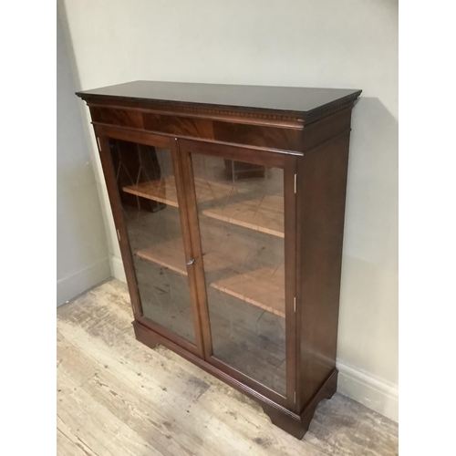 99 - A reproduction mahogany finish two door glazed bookcase on bracket feet