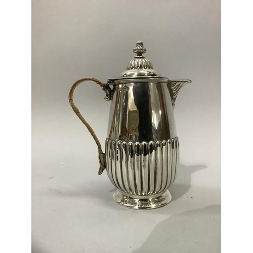 220 - A Victorian silver hot water jug, reeded base and lid with acorn finial and wicker covered handle, h... 