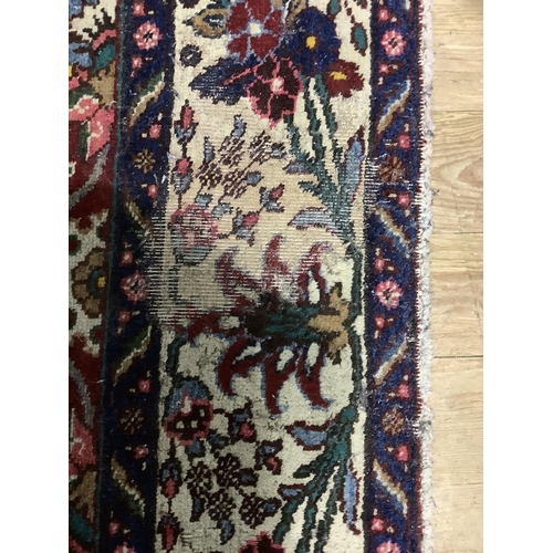 382 - A middle Eastern carpet having a crimson ground filled with flowering vines in ivory, blue, rose and... 