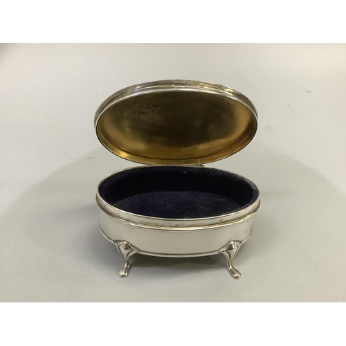 218 - A George V silver trinket box on four pad feet, oval outline with engine turned top and blue velvet ... 