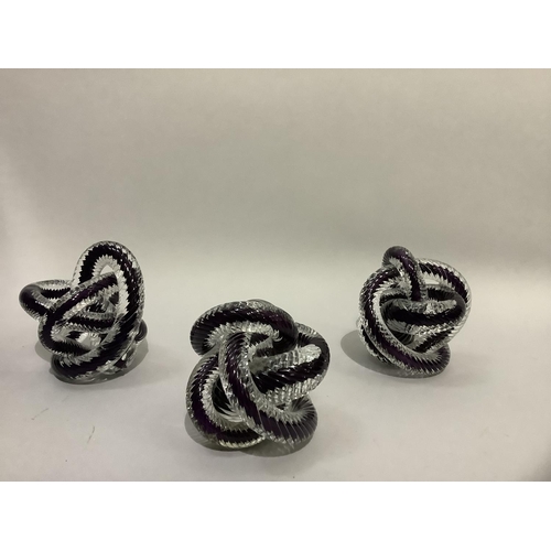 10 - A set of three purple and clear glass cased rope knots, 13cm high, one at fault