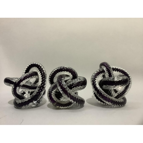 10 - A set of three purple and clear glass cased rope knots, 13cm high, one at fault