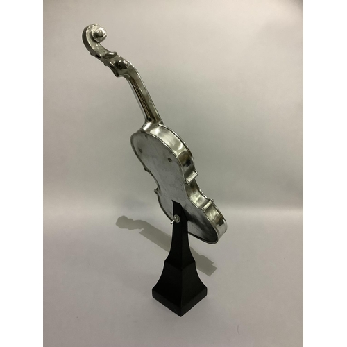 18 - A white metal violin raised on an ebonised pedestal,62cm high