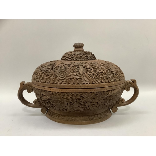 68 - A 20th century Indian carved hardwood two handled bowl and domed cover, all over carved with flowers... 