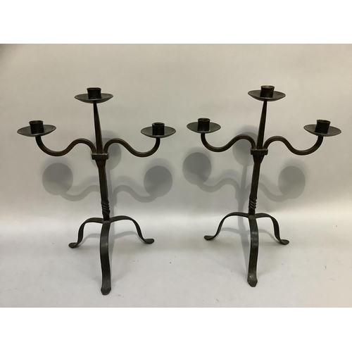 104 - A pair of wrought iron three light candlesticks on tripod base, 45.5cm high