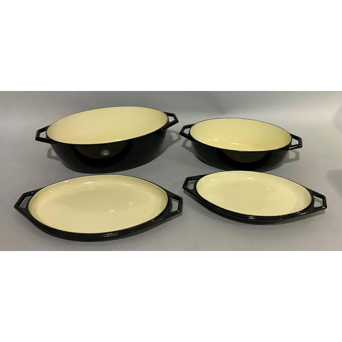 144 - Two Le Creuset black and cream casserole dishes of graduated size, oval form