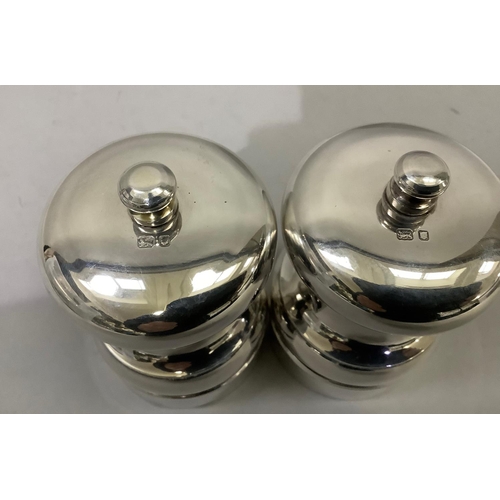 386 - A pair of silver salt and pepper mills of circular baluster form hallmarked London 1993 and 1994 for... 