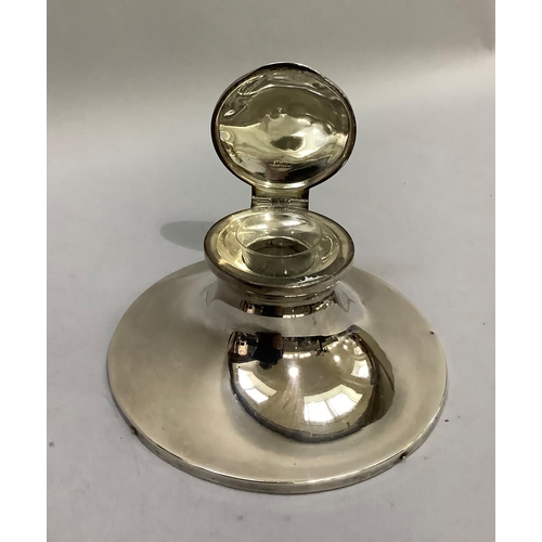 384 - A George V silver ink well of circular outline, hinged lid and clear glass liner and weighted base, ... 