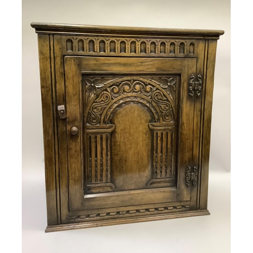 168 - An oak corner cupboard with arcaded frieze and arched panel to the single door