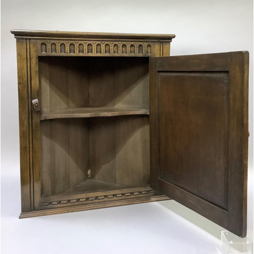 168 - An oak corner cupboard with arcaded frieze and arched panel to the single door