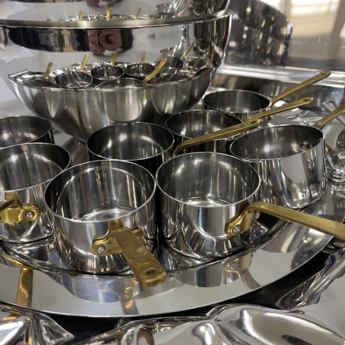 260 - A set of six individual stainless steel and brass handled saucepans, various platters and trays, lar... 