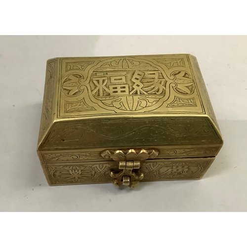 63 - A Chinese brass box having a canted lid with strapwork hinges and lock all over engraved with charac... 