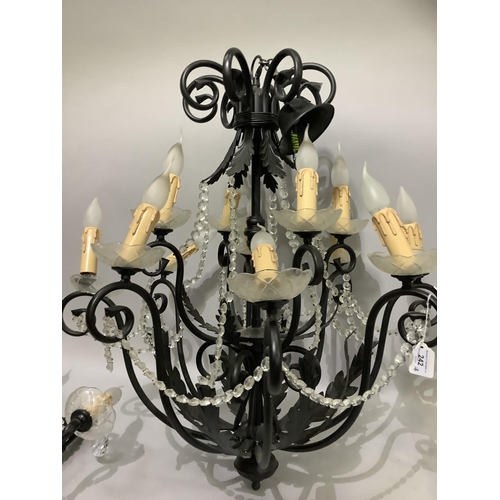 242 - A black metal twelve light chandelier with twelve scrolling arms interspersed with leaf branches, cu... 