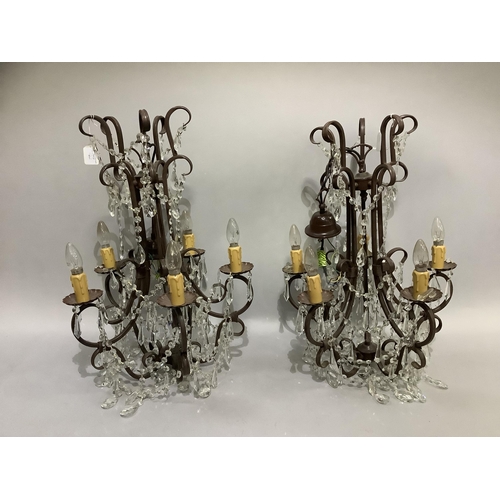 243 - A pair of brown wrought iron five light chandeliers, each having five scrolling branches, fluted sco... 