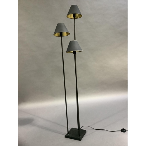 332 - A triple standard lamp, the three graduated height column lamps each with black shade and on a circu... 