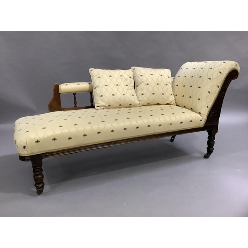 473 - An Edwardian mahogany chaise, the spindle back upholstered in bee patterned fabric, on turned legs w... 