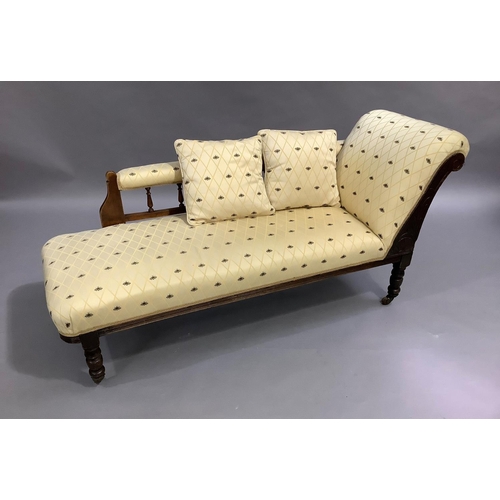 473 - An Edwardian mahogany chaise, the spindle back upholstered in bee patterned fabric, on turned legs w... 