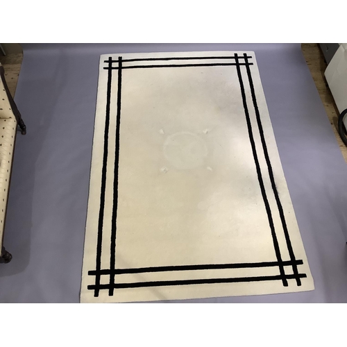 374 - A cream wool rug with twin black line border, 290cm x 200cm