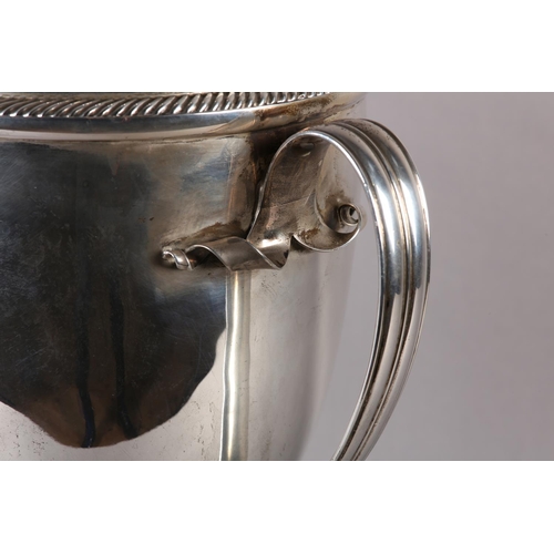 197 - A GEORGE V SILVER TROPHY CUP and domed cover with acorn finial, twin loop handles, gadroon rims, rai... 