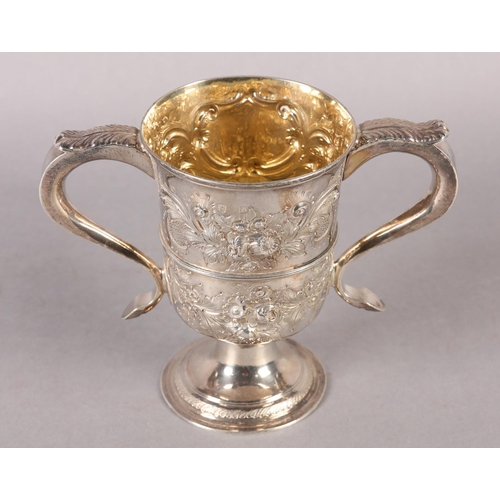 194 - A GEORGE III SILVER TROPHY CUP with rose chasing, banded with foliate c-scroll handles, later engrav... 