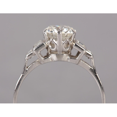 303 - A DIAMOND RING in platinum c.1950, the brilliant cut principal stone claw set and flanked by four gr... 