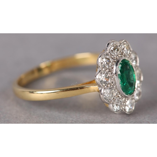 306 - AN EMERALD AND DIAMOND CLUSTER RING, the oval faceted emerald millegrain set within a surround of br... 