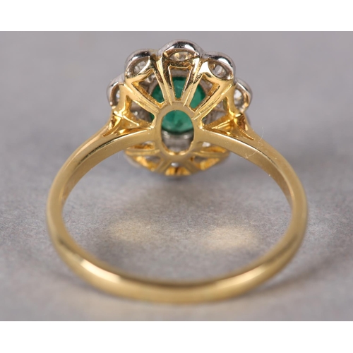 306 - AN EMERALD AND DIAMOND CLUSTER RING, the oval faceted emerald millegrain set within a surround of br... 