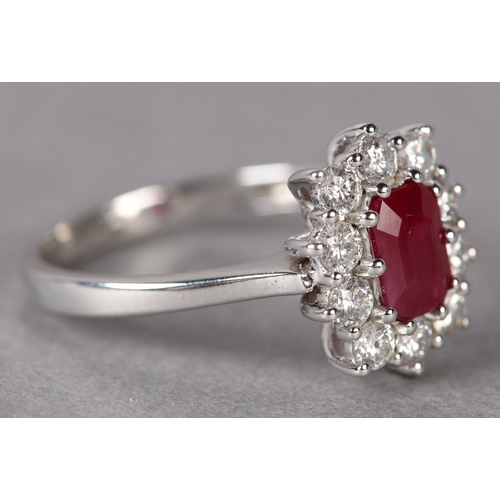 299 - A RUBY AND DIAMOND CLUSTER RING in 9ct white gold, claw set to the centre with a step cut ruby withi... 