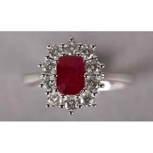 299 - A RUBY AND DIAMOND CLUSTER RING in 9ct white gold, claw set to the centre with a step cut ruby withi... 