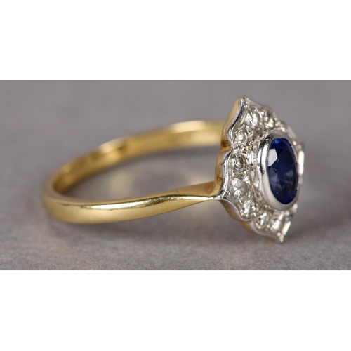 311 - A SAPPHIRE AND DIAMOND CLUSTER RING in 18ct yellow and white gold, the oval faceted sapphire collet ... 