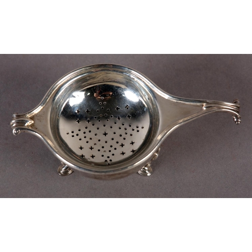 239 - A GEORGE V SILVER TEA STRAINER AND BOWL by Greenwood & Sons, Huddersfield with knurled scroll handle... 