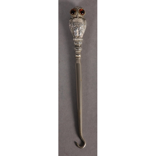 274 - A VICTORIAN SILVER OWL BUTTON HOOK, the double-sided handle as an owl with brown and blue glass eyes... 