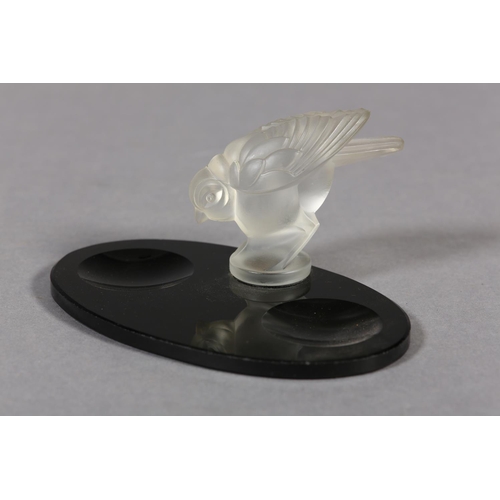 177B - A FRENCH MOULDED OPAQUE GLASS BIRD, mounted on a black glass desk tidy of oval outline, c.1930s, 17.... 