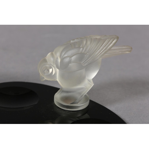 177B - A FRENCH MOULDED OPAQUE GLASS BIRD, mounted on a black glass desk tidy of oval outline, c.1930s, 17.... 