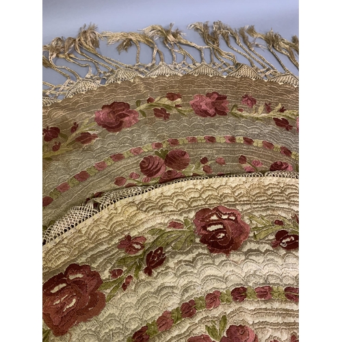 168 - A circular, silk embroidered table cover, with floral design, macramé fringing, worked in concentric... 