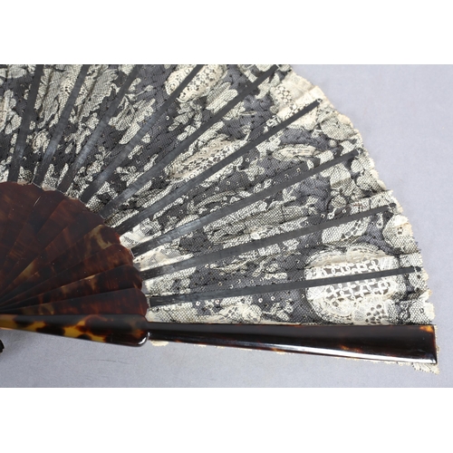 85 - c1905, a black net and mixed Brussels lace fan, the unusual needle lace floral motifs applied to bla... 