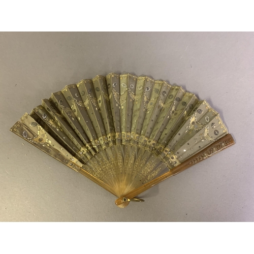 57 - A c.1905 pale horn fan, lightly gilded, with olive green silk leaf, cut away in places to reveal mus... 