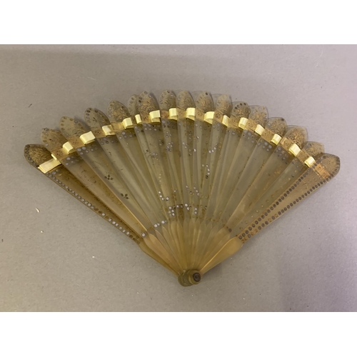 57 - A c.1905 pale horn fan, lightly gilded, with olive green silk leaf, cut away in places to reveal mus... 