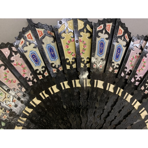 16 - Two unusual 20th century fans, the first a wood brisé painted black, the sticks shaped and pierced, ... 