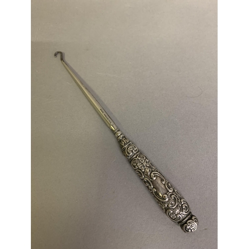 253 - A Victorian skirt lifter, a silver button hook with embossed handle and void for initials, marked fo... 