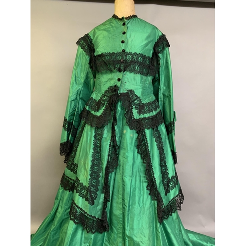 216 - A vibrant emerald green two-piece 1850’s costume, the bodice with long, pagoda sleeves, trimmed with... 