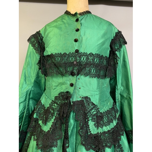 216 - A vibrant emerald green two-piece 1850’s costume, the bodice with long, pagoda sleeves, trimmed with... 