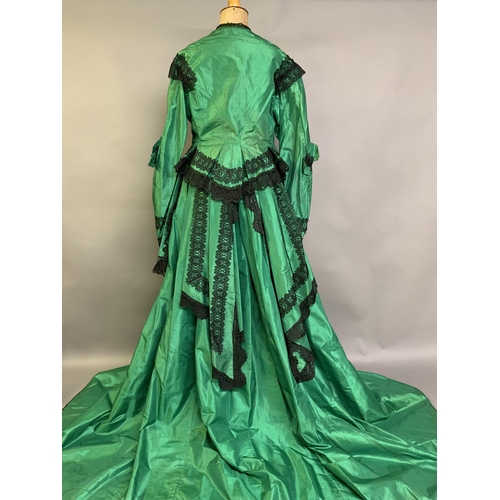 216 - A vibrant emerald green two-piece 1850’s costume, the bodice with long, pagoda sleeves, trimmed with... 