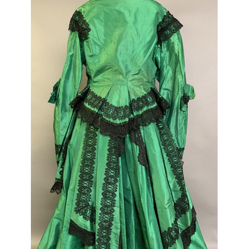 216 - A vibrant emerald green two-piece 1850’s costume, the bodice with long, pagoda sleeves, trimmed with... 